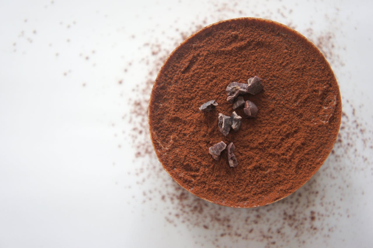Home Top view of a rich chocolate dessert dusted with cocoa powder on a white background.